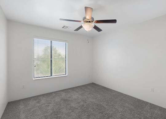 A room with a ceiling fan and a window with blinds.