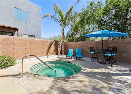 A small pool in a backyard with a table and chairs.