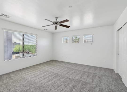 Bedroom with a ceiling fan and carpeted floor.
