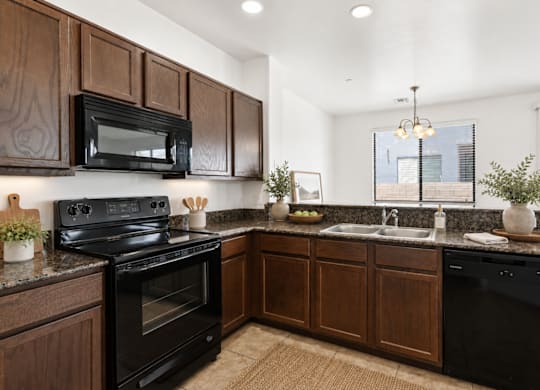 A kitchen with dark wood cabinets and black appliances.