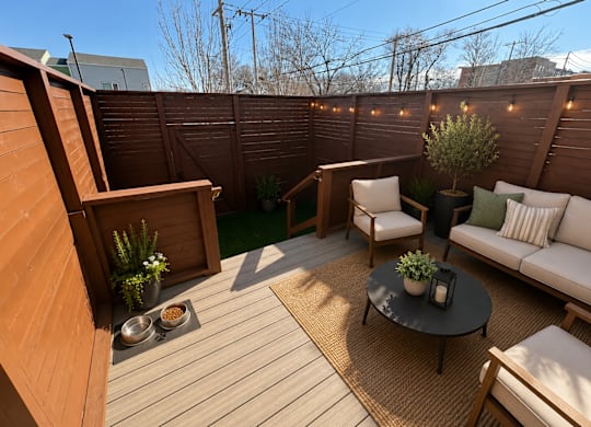 A wooden deck with a white couch and a table with a plant on it.
