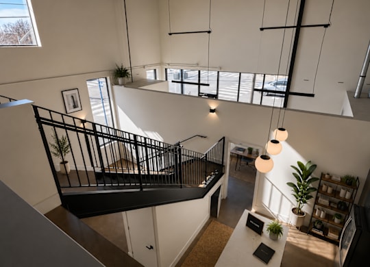 A black metal staircase with a white railing and a white table with a plant on it.