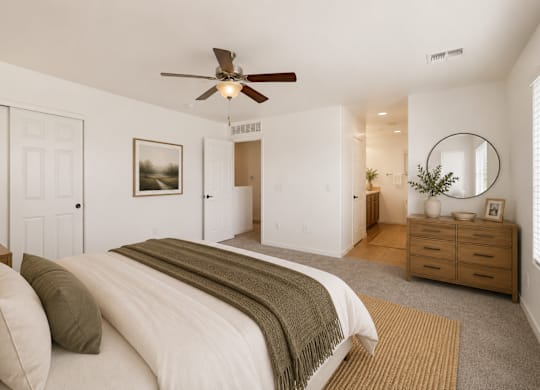 A bedroom with a large bed and a ceiling fan.