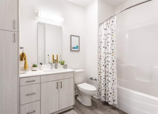A white bathroom with a toilet, sink, and shower.