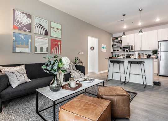A modern living room with a grey couch, a coffee table, and a kitchen in the background.
