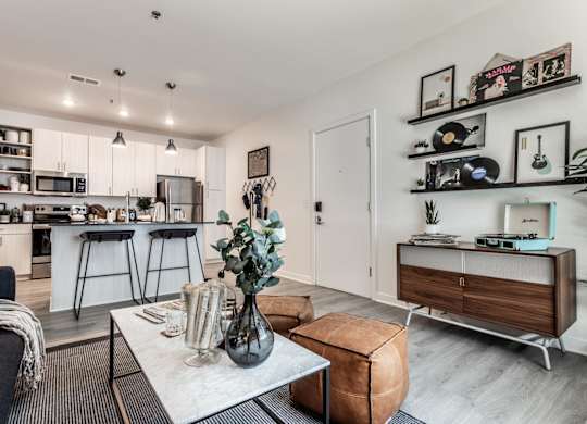 A modern living room with a kitchen in the background.