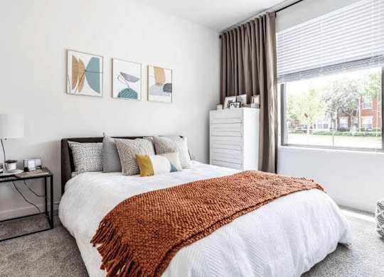 A bedroom with a large bed and a window overlooking a street.