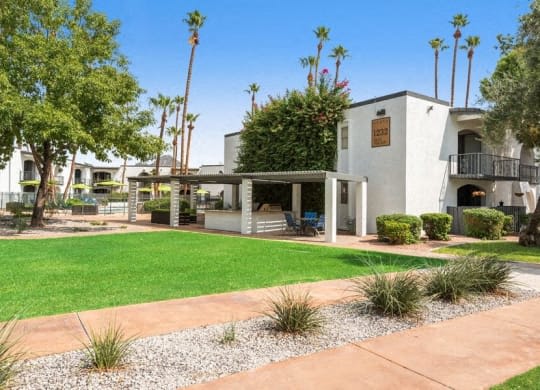 the front yard of a building with a green lawn and palm trees at Vertu, Arizona