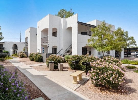 a white building with a sidewalk and a bench at Vertu, Phoenix, 85014