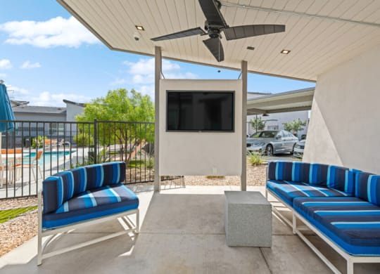 a patio with blue chairs and a tv on a wall at Baseline on 16, Arizona