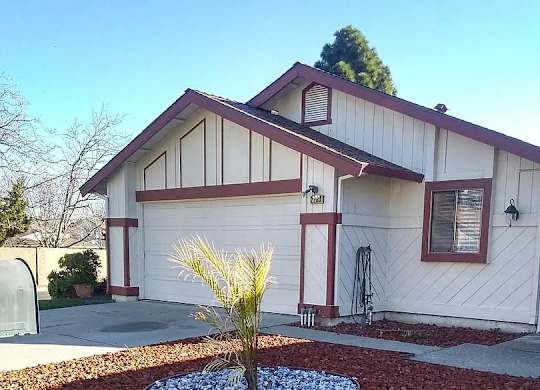 a white house with a garage and a palm tree