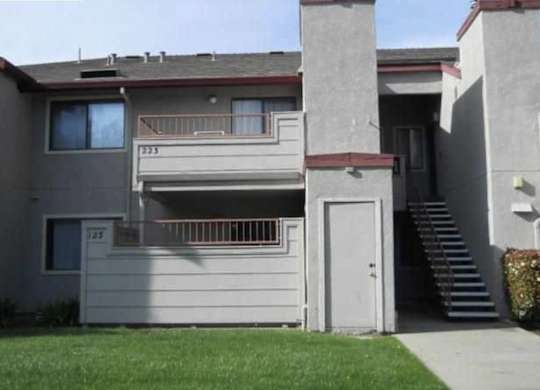 the front of a gray house with a white door