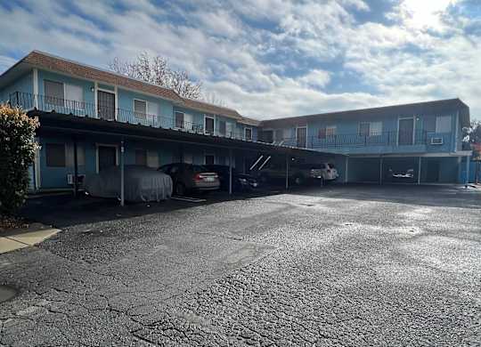 an empty parking lot in front of a motel with a cloudy sky