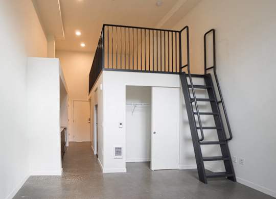 A black ladder is leaning against a white wall in a room with a white floor and a white ceiling.