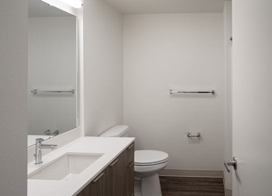 A white bathroom with a toilet, sink and mirror.