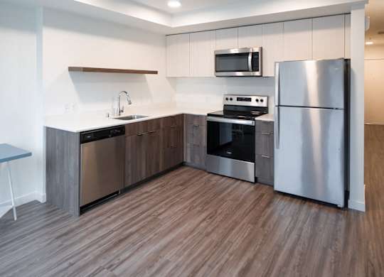 A modern kitchen with a wooden floor and stainless steel appliances.