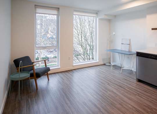 A chair sits in a room with a table and a refrigerator.