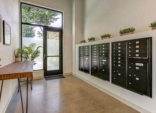 A room with a wooden table and a wall of mailboxes.
