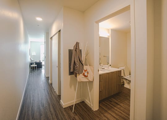 A small bedroom with a bed, a mirror, a toilet, and a wooden floor.