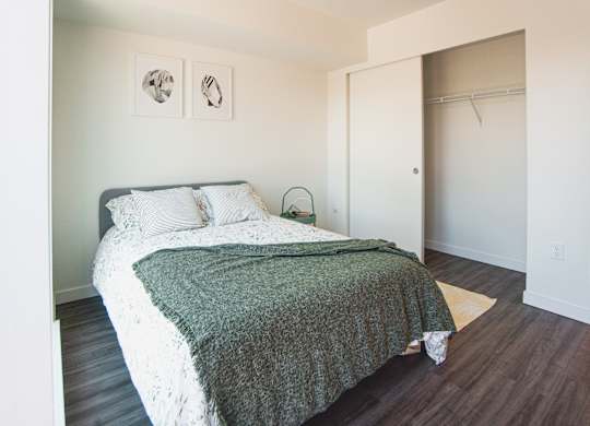 A bed with a green blanket and white pillows is in the room.