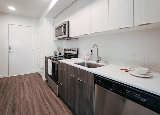 A kitchen with dark wood floors and white cabinets.