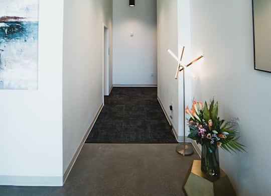 A long hallway with a bench and a vase of flowers.