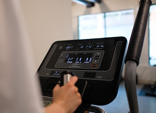 A person is using a treadmill with a digital display showing the time and other information.