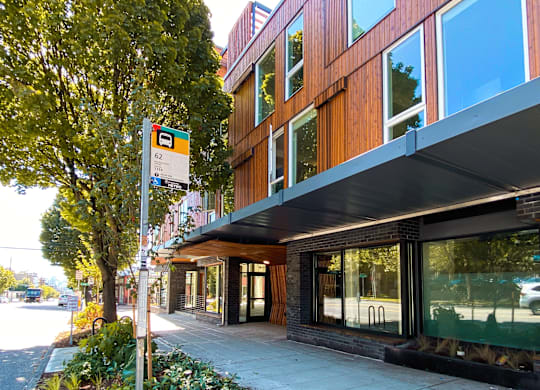 A modern building with a wooden facade and a green tree beside it.
