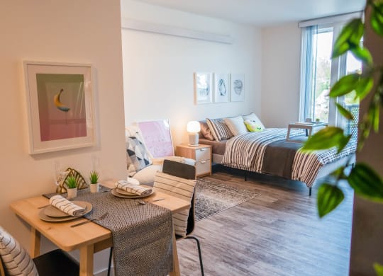a living room with a table and a bed in a bedroom