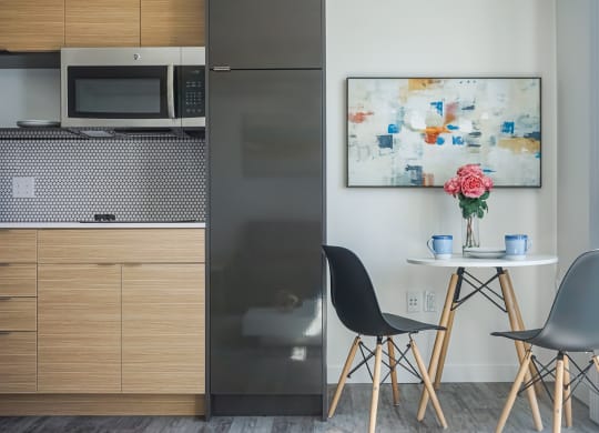 a kitchen with a stainless steel refrigerator and a table with two chairs