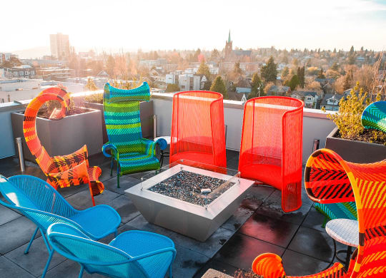 a terrace with colorful chairs and a fire pit    and a city