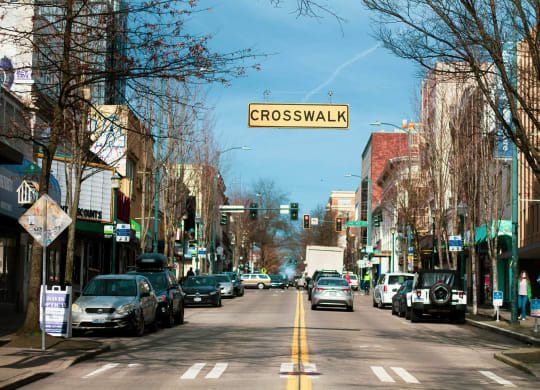 a city street with cars and a crosswalk sign