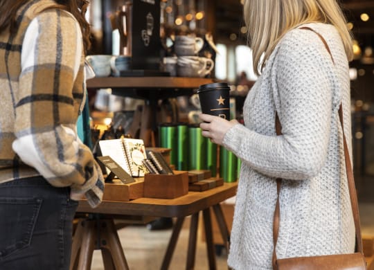 a woman holding a cup of coffee in a market