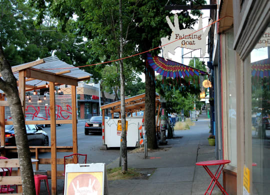 a city street with a cafe and tables on the sidewalk