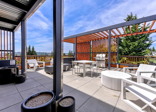 A patio with white chairs and a table is covered by a roof.