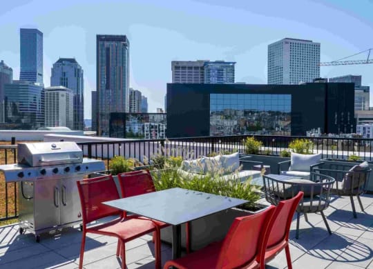 a rooftop patio with tables and chairs and a city in the background