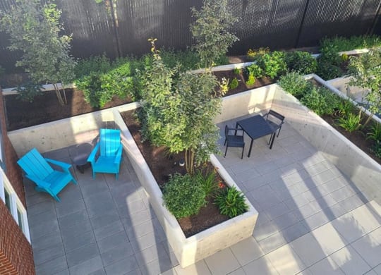 a patio with blue chairs and a table in a garden