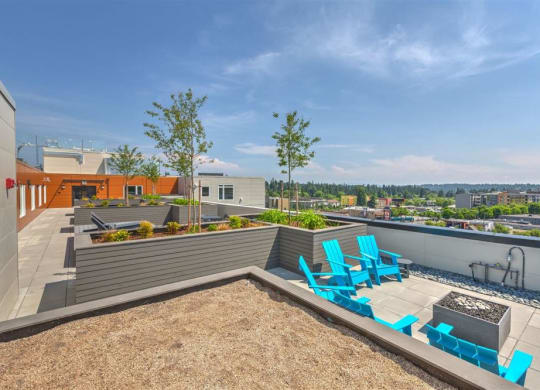 a rooftop patio with blue chairs and a fire pit