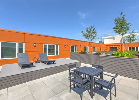 a patio with a table and chairs in front of an orange building