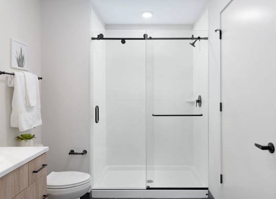 A white bathroom with a toilet, sink, and a walk-in shower.