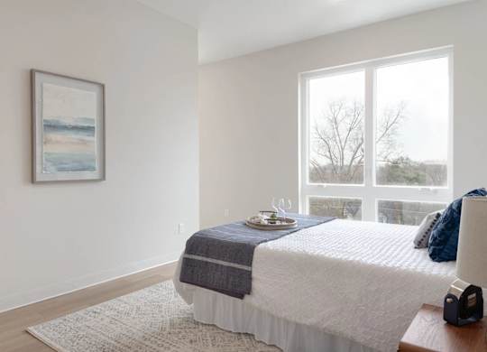 A bedroom with a bed, a nightstand, and a window.