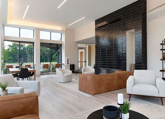 A modern living room with a brown leather couch and a white armchair.