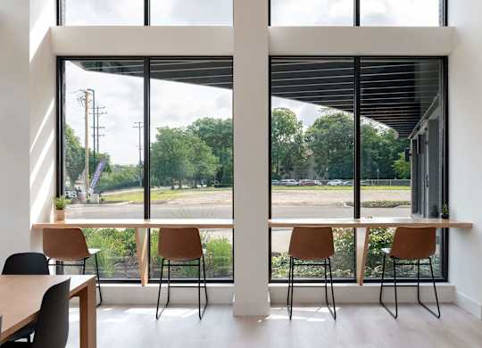 A room with a table and chairs in front of a large window with a view of the outside.
