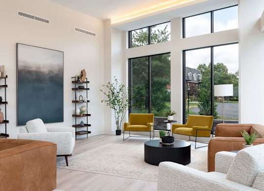 A living room with a large painting on the wall and a variety of furniture including a sofa, armchair, and a coffee table.