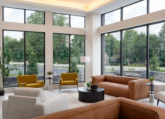 A living room with a large window and a view of trees and a road.