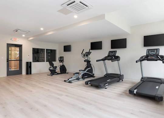A gym with treadmills, elliptical machines, and other exercise equipment.