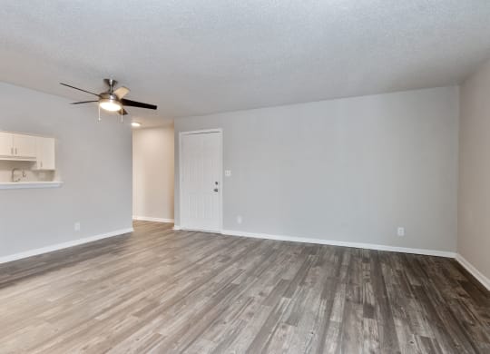 an empty living room with wood floors and a ceiling fan  at Eastwood Crossings, Kansas City, MO
