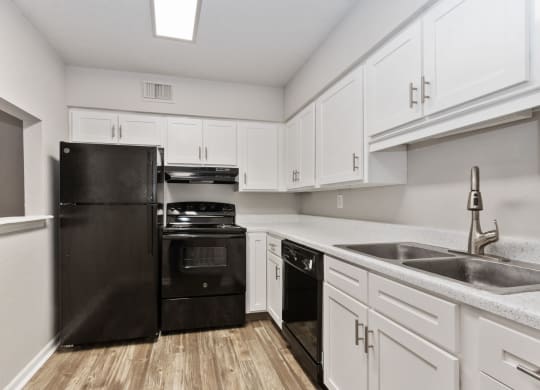 a kitchen with black appliances and white cabinets at Eastwood Crossings, Kansas City, 64129