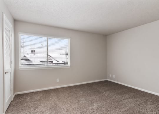 an empty bedroom with a window and carpeted floor at Eastwood Crossings, Missouri, 64129