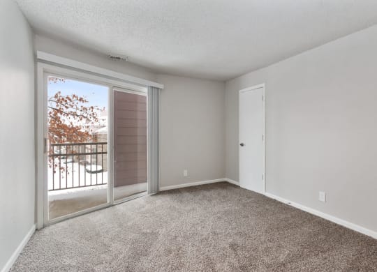 an empty living room with a sliding glass door to a balcony at Eastwood Crossings, Kansas City, Missouri